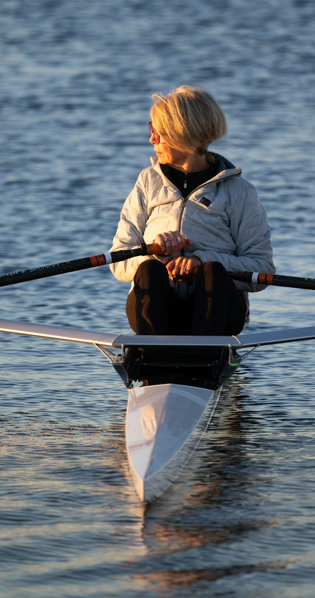 A senior woman embraces an active retirement, rowing peacefully at sunrise in Sarasota. Watching the sunrise over the lake.